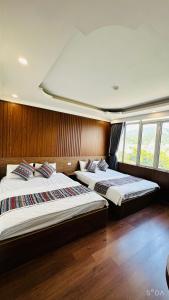 高平Minh Hoang Hotel & Homestay的配有木墙和窗户的客房内的两张床