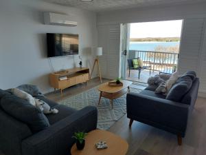 卡伦德拉Sandy Shores Holiday Units的一间带两张沙发的客厅,享有水景