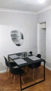 里约热内卢Magnífico apartamento的餐桌、黑色椅子和镜子