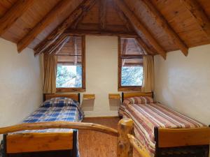 圣卡洛斯-德巴里洛切Cabaña El Viaje的一间卧室设有两张床和两个窗户。