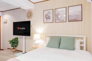 大阪アリタハイツ難波502的卧室配有白色的床和平面电视。