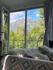 拉安戈斯图拉镇Casa moderna en el bosque y montaña的美景大窗户前的一张床位