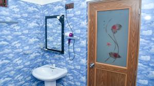 丹不拉Prem Nadee Hotel的浴室设有卫生间和水槽,墙上涂有云彩。
