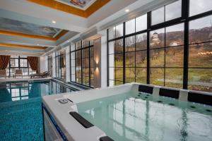拉姆尼库沃尔恰Hotel NOBLESSE Boutique&Spa的一座带窗户的大型游泳池