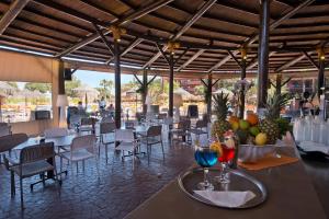 福恩吉罗拉福恩吉罗拉海滩旅游公寓的餐厅设有桌椅,并在桌子上提供水果
