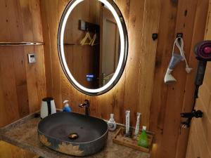 苏州枕窗听雨客栈（(苏州观前拙政园店）的浴室水槽和木制墙上的圆镜子