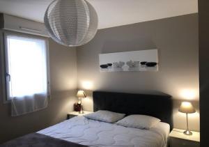 勒特隆歇Les cottages du golf的一间卧室配有一张床、两盏灯和一个窗户。
