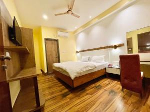 瓦拉纳西Hotel SHIVAM ! Varanasi Forɘigner's-Choice ! fully-Air-Conditioned-hotel, lift-and-Parking-availability near-Kashi-Vishwanath-Temple and-Ganga-ghat的一间卧室配有一张床、一台电视和一把椅子