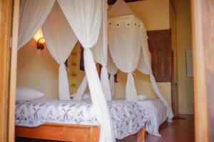 Gili GedeYut's Inn Flower Paradise Gili Gede的卧室配有2张带白色窗帘的床