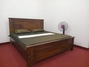 加姆波勒Idom Cozy的配有风扇的客房内的一张木床
