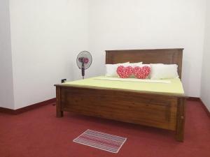 加姆波勒Idom Cozy的一张带两个红色和白色枕头的床和风扇