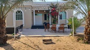 拉斯阿尔卡麦Villa 9 Palms Beach的房屋前设有带桌椅的天井。