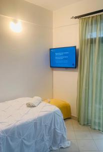 蒙巴萨Moraa’s Home的一间设有床铺和墙上电视的客房