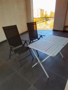 科森扎Uniclub House的阳台上配有两把椅子和一张白色桌子