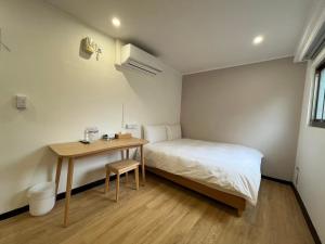台北宏洲旅社HZ Hotel的一间小卧室,配有一张床和一张桌子