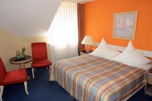 伊尔梅瑙伊尔梅瑙霍夫酒店的酒店客房,配有一张床和两张红色椅子