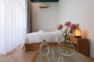顺化Lemi - Homestay in Hue的一间卧室配有一张床和一张花瓶桌子