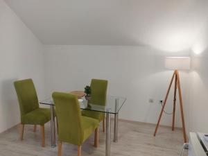 索科矿泉村Studio Andrijana Sokobanja的一间设有玻璃桌和绿色椅子的用餐室