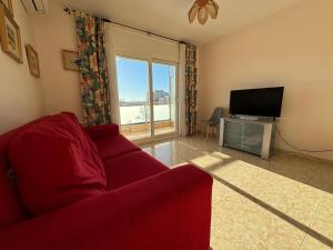 罗萨斯Piso en el centro con vistas al mar y balcón的客厅配有红色沙发和电视