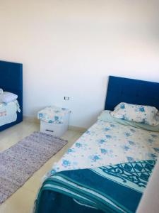阿斯旺Shipa's nubian house的一间卧室配有一张带蓝色床头板和2个地毯的床。