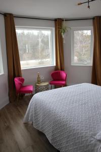 贝尔维尔4 Guest Suite with Waterfront Views at Fancie's PEC的一间卧室配有一张床和两张粉红色的椅子