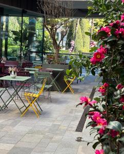 加尔达湖滨贾迪诺威尔第酒店的庭院配有桌椅和粉红色的鲜花