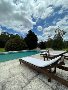 坦迪尔Quinta Siete Soles的游泳池旁设有长凳和桌子