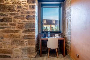 保罗Cherry Sculpture Hotel的带石墙的客房设有书桌和窗户。