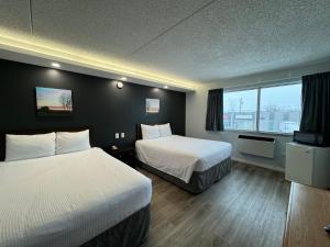 温尼伯Travelodge by Wyndham Winnipeg的酒店客房设有两张床和窗户。