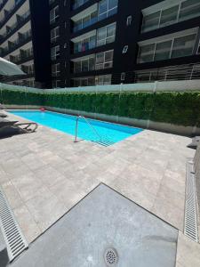 圣地亚哥Apartamento en Santiago centro cerca de movistar arena, caupolican的大楼前的游泳池