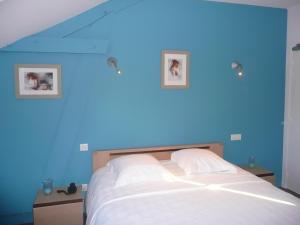 彻尔维尔圣欧班酒店的蓝色卧室配有一张墙上有两张照片的床
