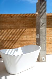 埃斯孔迪多港Casa SANA的木制墙壁前的白色浴缸