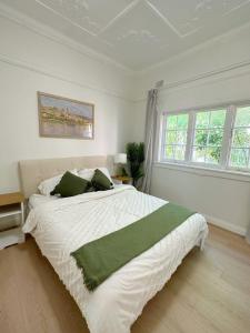 悉尼three bedroom house within walking distance to light rail station的白色卧室配有一张带绿色枕头的大床