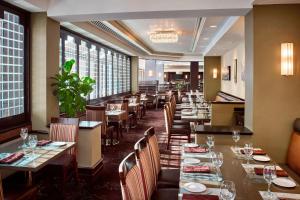 汉密尔顿喜来登汉弥敦酒店的餐厅设有长桌子、椅子和窗户。