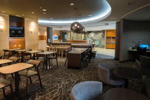 温斯顿·塞勒姆SpringHill Suites by Marriott Winston-Salem Hanes Mall的一间带桌椅的餐厅和一间酒吧