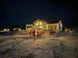 弗罗达尔Lakefront Villa, exclusive leisure property near Vrådal Golf, Straand Summerland & Panorama Ski center的一群人站在房子前面的雪中