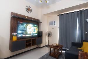 马尼拉The Radiance Manila Bay Condo unit的客厅配有电视、沙发和时钟