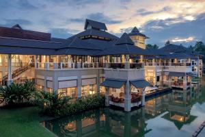 清莱Le Meridien Chiang Rai Resort, Thailand的一座倒映在水中的大建筑