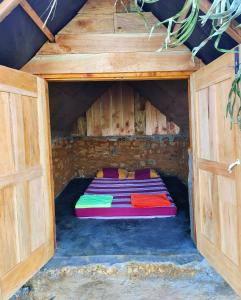哈普特莱Eco Lodge Haputale-Camping Sri lanka的木房子的一张床铺,门打开