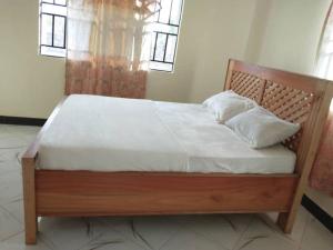 Boma la Ngombe4 BR/5 Bathroom Bungalow的卧室内的一张带白色床单和枕头的木床