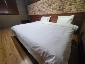 利川市Mokhwa Motel的卧室里一张大白色的床,卧室里设有砖墙