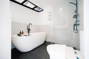 Bang SuMitt Haus (Lat Phrao Soi 5)的白色的浴室设有浴缸和卫生间。