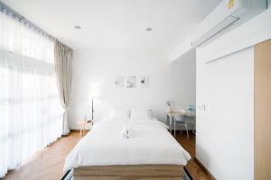 Bang SuMitt Haus (Lat Phrao Soi 5)的白色卧室配有床和桌子