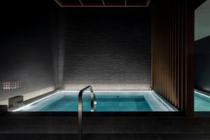 富良野Nozo Hotel的带淋浴的浴室内的热水浴池