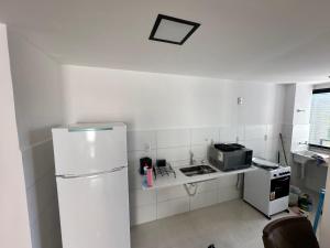 伊列乌斯Apartamento Para Temporada的白色的厨房配有冰箱和微波炉。