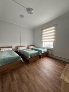 卡拉科尔Sayak hostel的客房内设有两张床,铺有木地板,设有窗户。