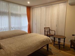 FuchisakiLa Classe Angel Road 2 - Vacation STAY 71507v的一间卧室设有两张床、一把椅子和一个窗户。
