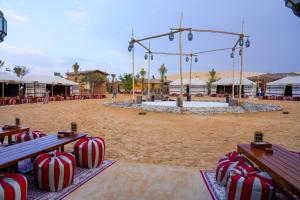 HunaywahAl Khayma Camp "Elite Camping & Dining in Experience"的海滩上摆放着红色和白色的糖果,坐在长椅上