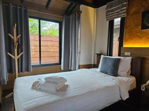 清迈R1 Resort Rajapruek Chiangmai的一间卧室配有一张大床和毛巾