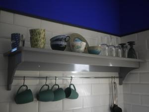 普卢阿Nature, Mer, Golf & Decouvertes...的厨房里的书架,有杯子和餐具